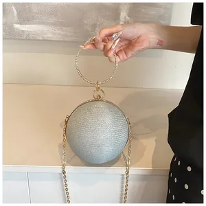 Detail of spherical evening bag with silver glitter finish and diamond gold handle
