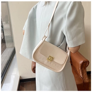 Detail of beige quilted flap bag with gold rectangular clasp and smooth leather trim