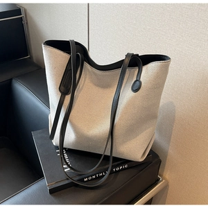 Detail shot of the contrast leather trim and premium canvas texture on a large tote bag