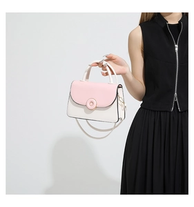 Detail view of stylish pink and white color-block handbag with ring buckle and thin strap