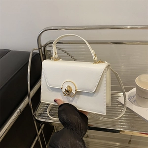 White structured handbag with gold circular clasp and detachable strap on display