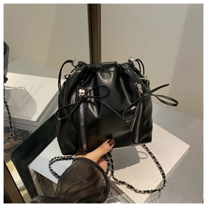 Detail of black leather bucket backpack with silver bow zippers and chain straps