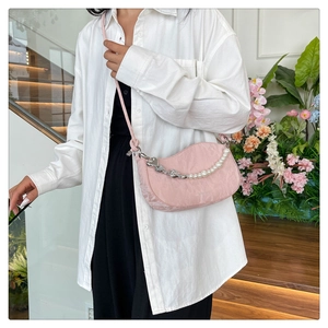 Detail of light pink crescent bag with pearl and heart chain on a minimalist shoulder strap