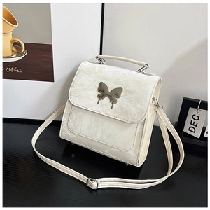 Close-up of ivory pleated leather shoulder bag with a silver butterfly metal buckle
