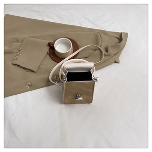 Top view of two-tone crossbody bag with brown suede flap and silver metal twist lock