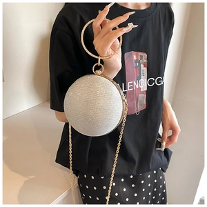 Detailed view of a silver spherical evening bag with glittering finish and golden ring handle