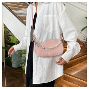 Detail view of pink crescent shoulder bag with pearl heart chain on a female model