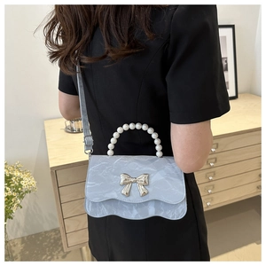 Detail of light blue marble handbag featuring white pearl handle and silver bow buckle