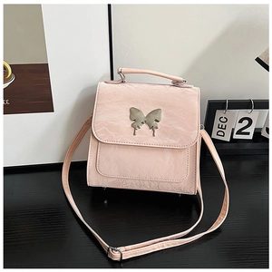 Detail of light pink pleated leather handbag with silver butterfly charm and metal feet