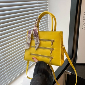 Bright yellow crossbody tote bag with decorative zippers and silk scarf on top handle