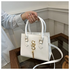 Detailed close-up of white crossbody bag featuring golden SSS logo and tassel charm