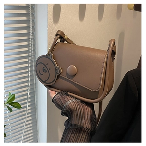 Détail du sac besace marron avec boucle ronde et pendentif en forme d'ours mignon