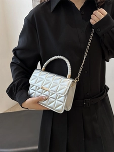 Silver quilted crossbody bag with gold chain strap and metal lock shown on model