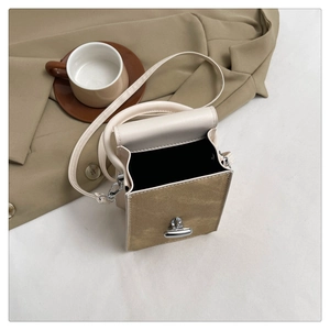 Detail of minimalist cream and khaki crossbody bag with silver rotating clasp closure
