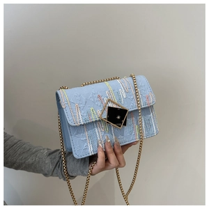 Detail of light blue crossbody bag featuring colorful stripes and golden chain strap