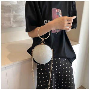 Detailed view of silver glitter sphere evening bag with gold ring handle and chain strap