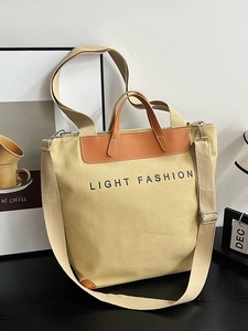 Minimalist beige canvas tote bag with brown leather handles and adjustable shoulder strap