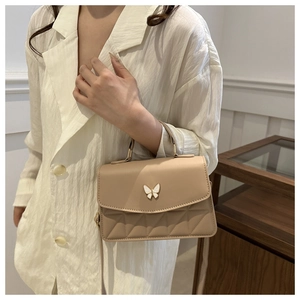Detail showing apricot quilted crossbody bag with butterfly hardware and chic stitching
