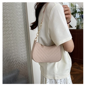 Detail of pink faux leather underarm bag featuring V-quilted texture and gold chain strap