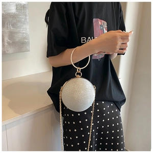 Detail of spherical evening bag with silver sequins and golden circular metal handle