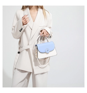 Chic blue and white patchwork crossbody bag shown styled with a beige suit on a model
