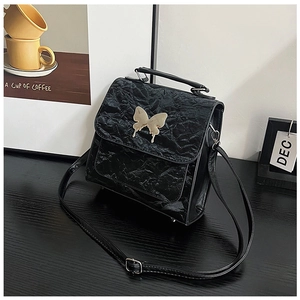 Close-up of black pleated PU leather texture with elegant golden butterfly buckle
