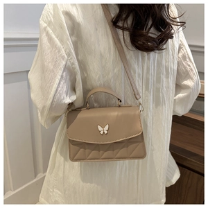 Detailed view of beige PU leather bag with white butterfly clasp and quilted pattern