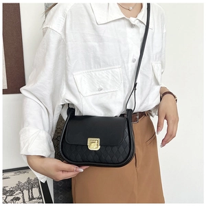 Detail of black quilted leather crossbody bag with elegant gold rotary clasp closure