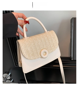Detail of white leather handbag with woven straw texture lid and round gold metal buckle