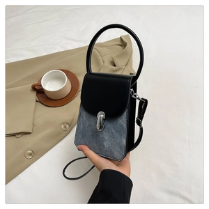 Detail of minimalist mixed-material handbag with round ring handle and metal clasp