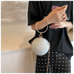 Detailed macro view of a silver sequined spherical handbag with a golden metal ring handle