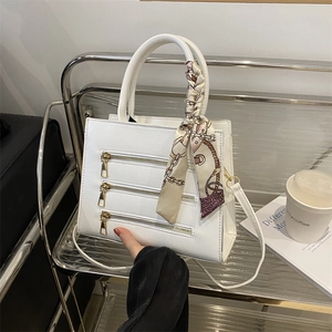 Detail of white PU leather bag with decorative zippers and silk scarf handle