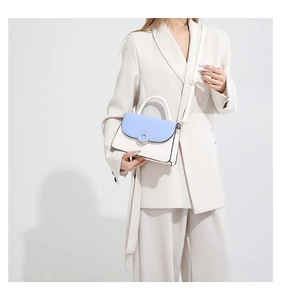 Detail of blue and beige crossbody bag with gold circular lock and thin leather strap