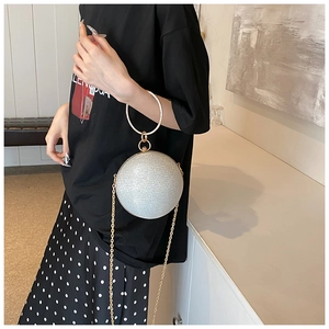 Detailed close-up of a silver spherical evening bag with glittering sequins and gold chain