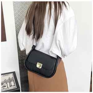 Chic black crossbody bag with gold buckle and diamond quilted pattern on a model