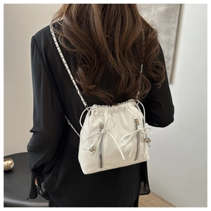 Detailed back view of a white leather bucket backpack with silver chains and bows