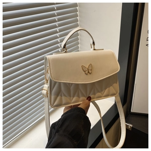Details der weißen Stepptasche mit goldener Schmetterlingsschließe und Handgriff