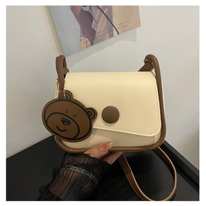 Détails du sac selle crème avec boucle magnétique marron et charmant ours suspendu