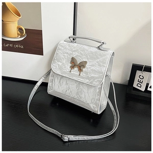 Detail of silver pleated texture handbag with a metallic butterfly clasp decoration