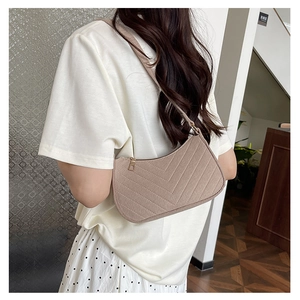 Detail view of beige hobo bag featuring V-shaped quilting and smooth zipper texture