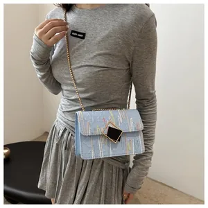 Light blue crossbody bag with colorful wavy embroidery and golden chain strap on model