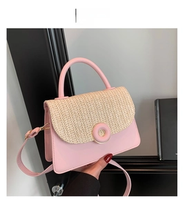 Detail of pink faux leather and woven straw crossbody bag with circular buckle accent