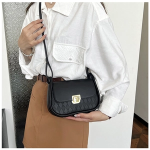 Detail of black crossbody bag featuring diamond quilted pattern and gold square lock