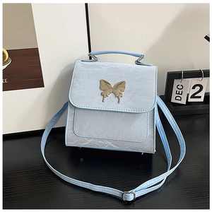Detailed close-up of light blue textured PU leather bag with silver butterfly emblem