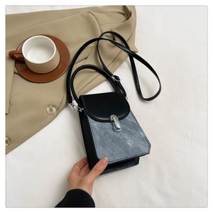Detailed top view of a minimalist two-tone handbag with silver lock and shoulder strap