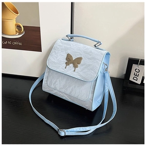 Close-up of light blue pleated handbag featuring a gold butterfly buckle and texture