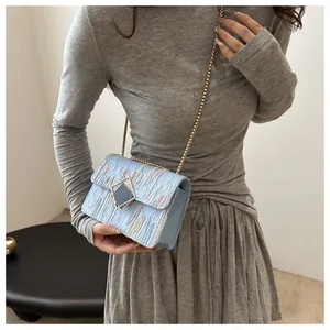 Detail of light blue textured crossbody bag with color stripes and golden chain strap