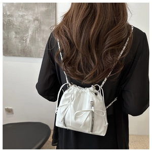 Rear view of model wearing a white leather drawstring backpack with chain straps