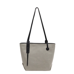 Minimalist canvas bucket bag with black leather shoulder straps on a clean white background