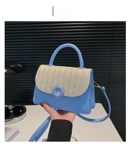 Detail of blue crossbody bag with cream woven flap and elegant gold-trimmed buckle